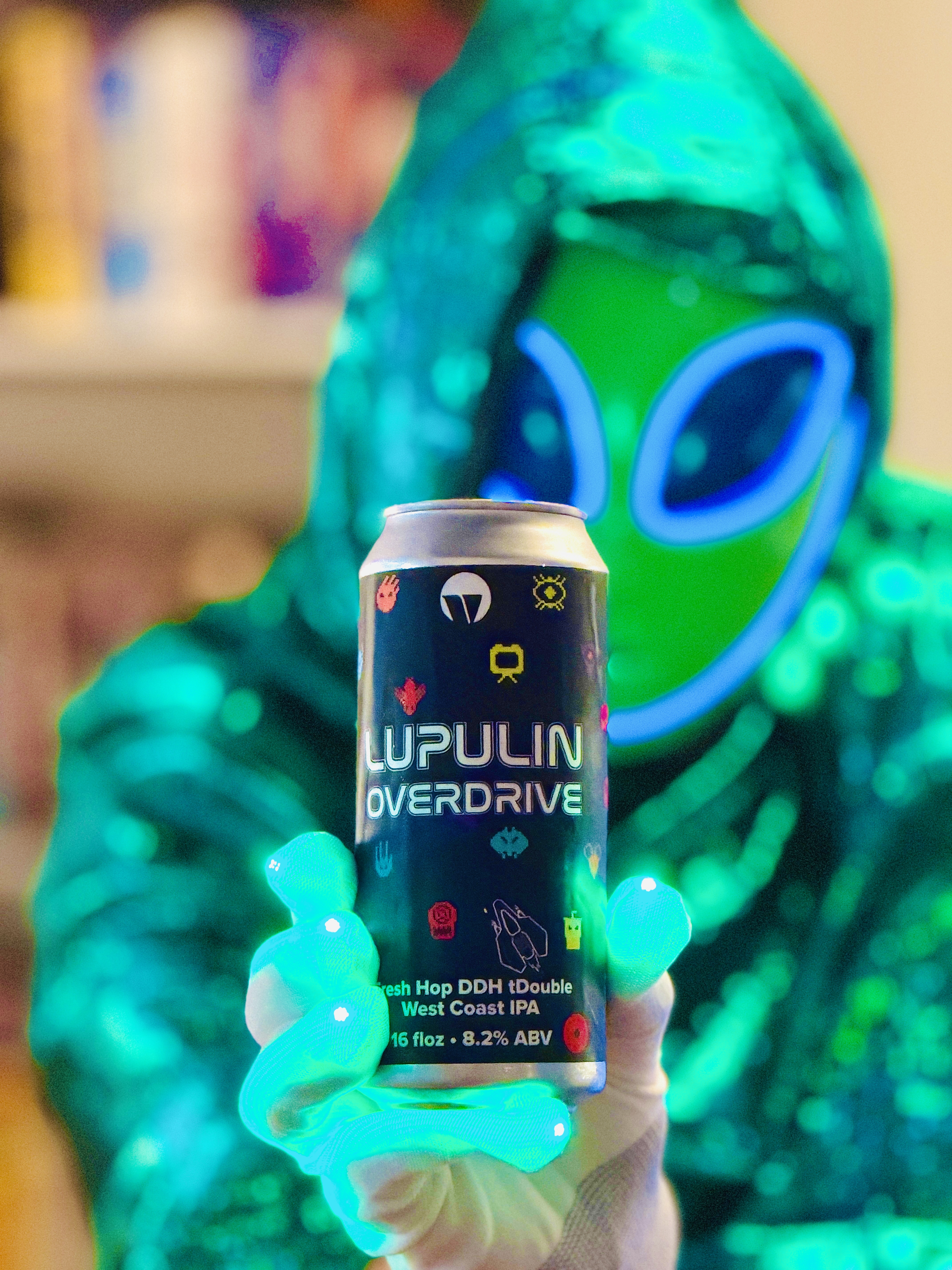 Alien holding a can of Lupulin Overdrive amid cyan lights